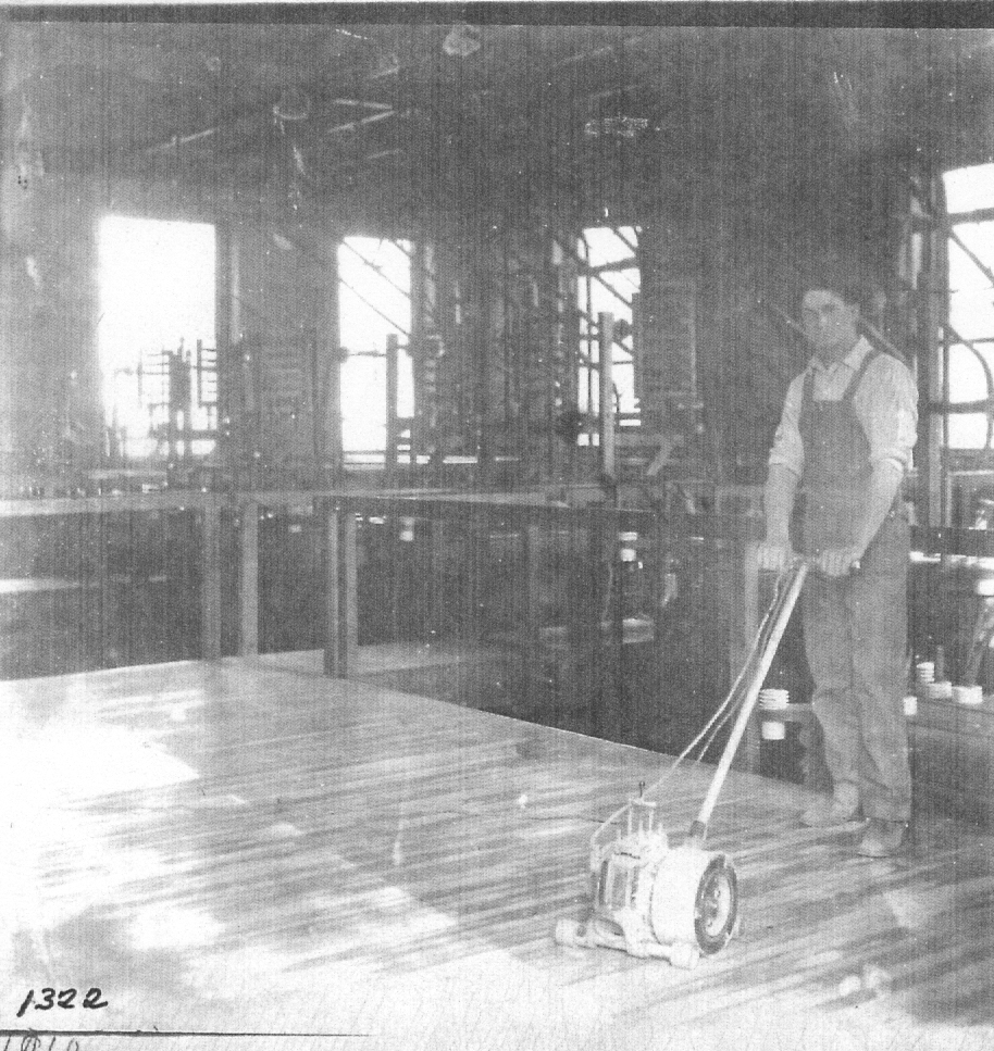 Black and white photo of an employee buffing the wood floors at the old power house
