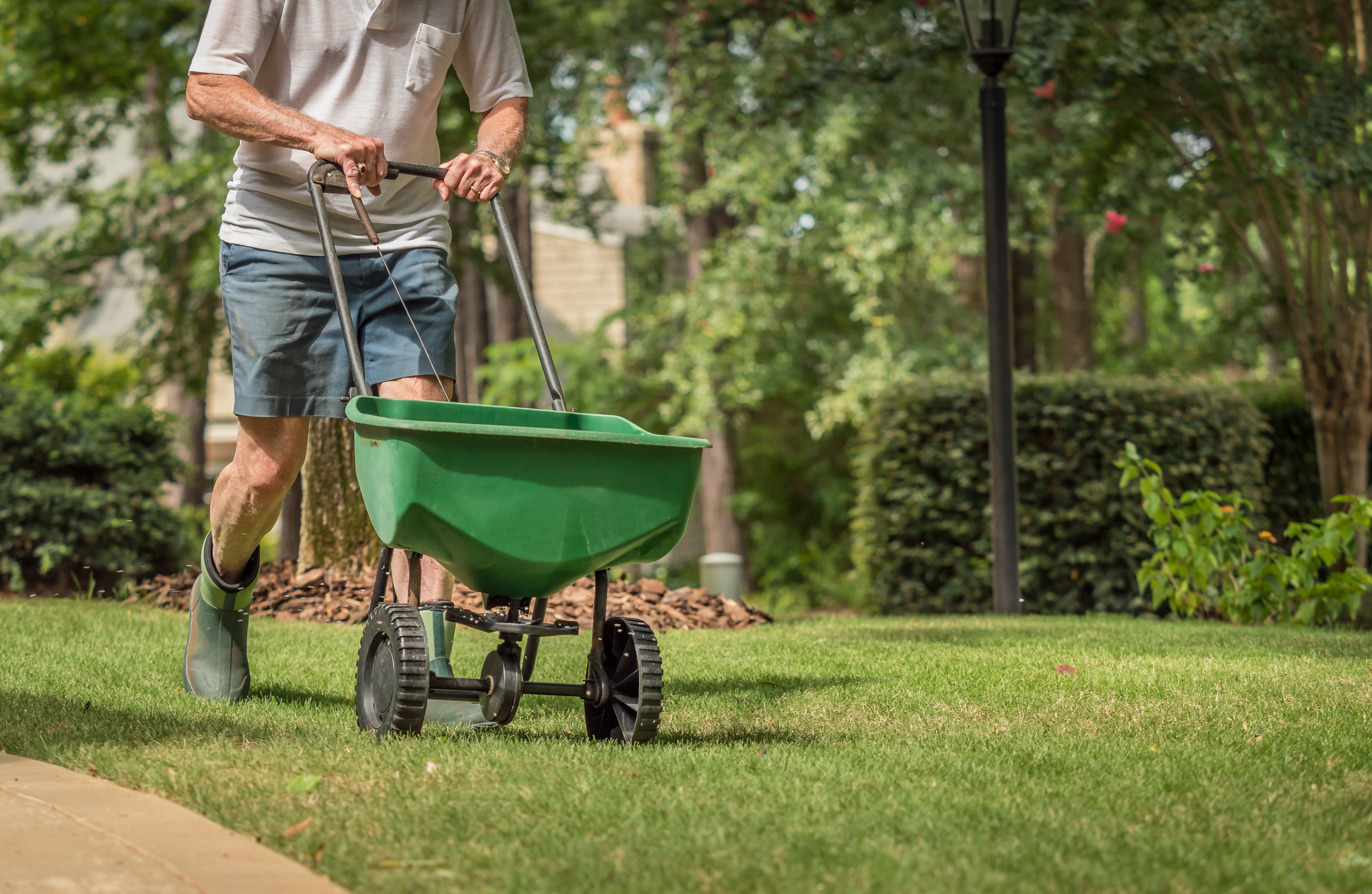 man pushing fertilizer truck on grass
